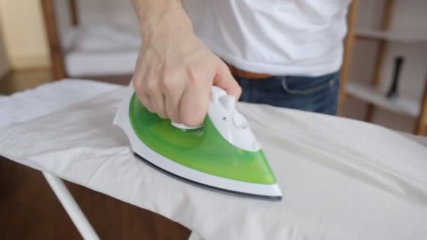Primer plano del joven planchando la ropa en la tabla de planchar en casa — Vídeos de Stock