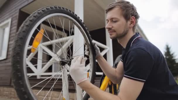 Młody brodaty mężczyzna naprawiający zepsuty rower — Wideo stockowe