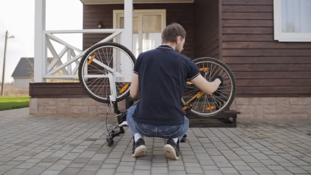 Rowerzysta sprawdza koło rowerowe, naprawa roweru, widok z tyłu — Wideo stockowe