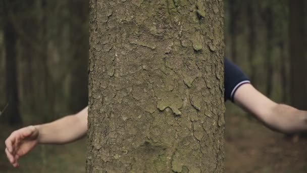 Uomo che abbraccia un grosso tronco d'albero nella foresta — Video Stock