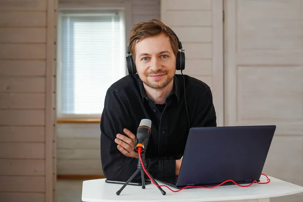 Portrait of influencer podcast creator streaming audio broadcast at his home. Broadcasting an interview using microphone Royalty Free Stock Photos