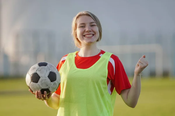 Šťastná fotbalistka ve sportovním oblečení slaví vítězství, drží fotbalový míč — Stock fotografie