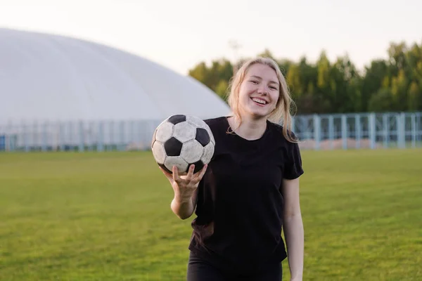 Portrét fotbalistky držící míč na fotbalovém hřišti při západu slunce — Stock fotografie