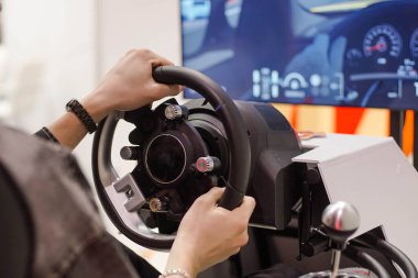 Tema parkında büyük ekran monitörüyle yarış simülatörü oyunu oynayan genç adam.