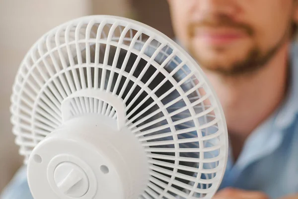 Hombre disfrutando del flujo de aire de ventilador en la oficina. Empresario refrescante delante del ventilador eléctrico. Calor de verano. —  Fotos de Stock