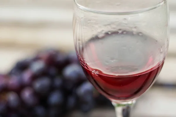 Copo de vinho tinto com um monte de uvas em fundo de madeira, close-up — Fotografia de Stock