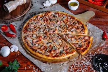 Mutfak masasında uzanmış pizza, malzemeler etrafa saçılmış..