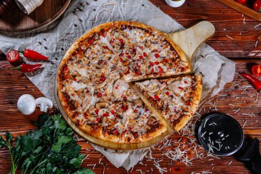 Mutfak masasında uzanmış pizza, malzemeler etrafa saçılmış..