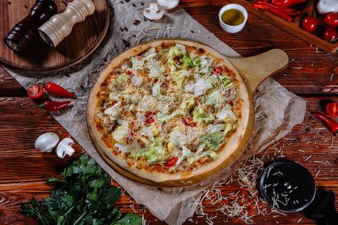 Mutfak masasında uzanmış pizza, malzemeler etrafa saçılmış..