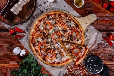 Mutfak masasında uzanmış pizza, malzemeler etrafa saçılmış..