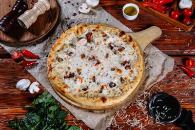 Mutfak masasında uzanmış pizza, malzemeler etrafa saçılmış..