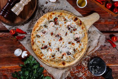 Mutfak masasında uzanmış pizza, malzemeler etrafa saçılmış..