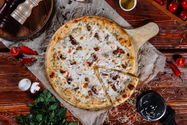 Mutfak masasında uzanmış pizza, malzemeler etrafa saçılmış..