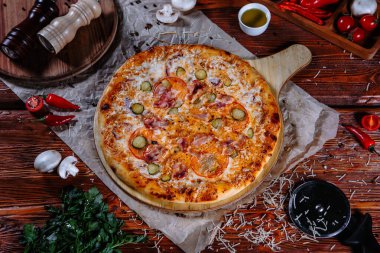 Mutfak masasında uzanmış pizza, malzemeler etrafa saçılmış..