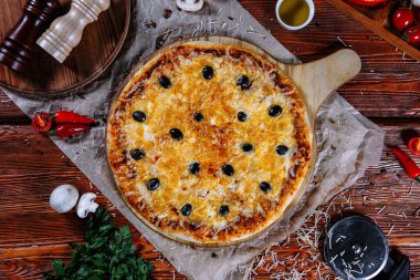 Mutfak masasında uzanmış pizza, malzemeler etrafa saçılmış..