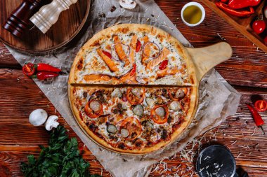 Mutfak masasında uzanmış pizza, malzemeler etrafa saçılmış..