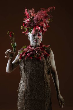 Kil bulaşmış bir kız. Modelde çiçeklerden yapılmış bir başlık var..