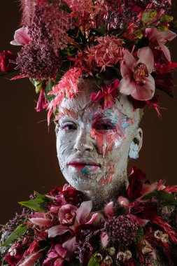 Kil bulaşmış bir kız. Modelde çiçeklerden yapılmış bir başlık var..