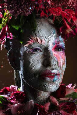 Kil bulaşmış bir kız. Modelde çiçeklerden yapılmış bir başlık var..