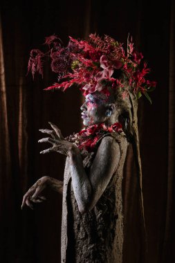 Kil bulaşmış bir kız. Modelde çiçeklerden yapılmış bir başlık var..