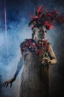 Kil bulaşmış bir kız. Modelde çiçeklerden yapılmış bir başlık var..