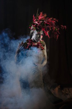 Kil bulaşmış bir kız. Modelde çiçeklerden yapılmış bir başlık var..