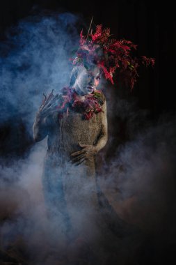 Kil bulaşmış bir kız. Modelde çiçeklerden yapılmış bir başlık var..