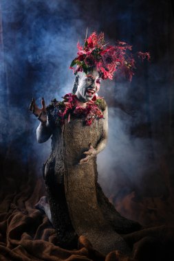 Kil bulaşmış bir kız. Modelde çiçeklerden yapılmış bir başlık var..