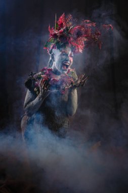 Kil bulaşmış bir kız. Modelde çiçeklerden yapılmış bir başlık var..