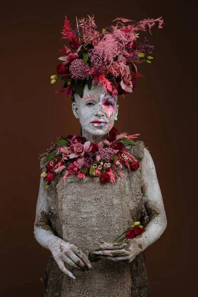 Kil bulaşmış bir kız. Modelde çiçeklerden yapılmış bir başlık var..