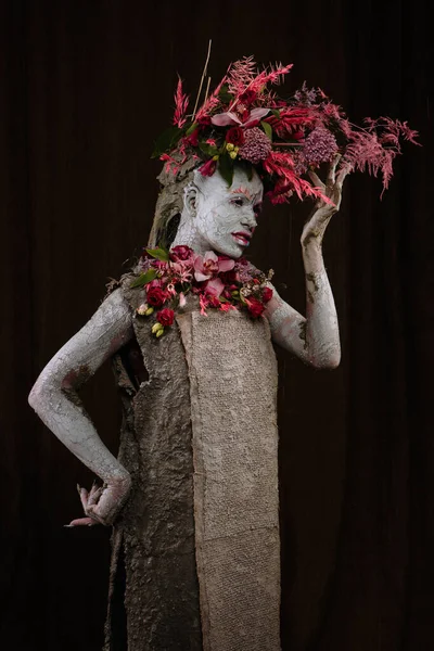 Kil bulaşmış bir kız. Modelde çiçeklerden yapılmış bir başlık var..