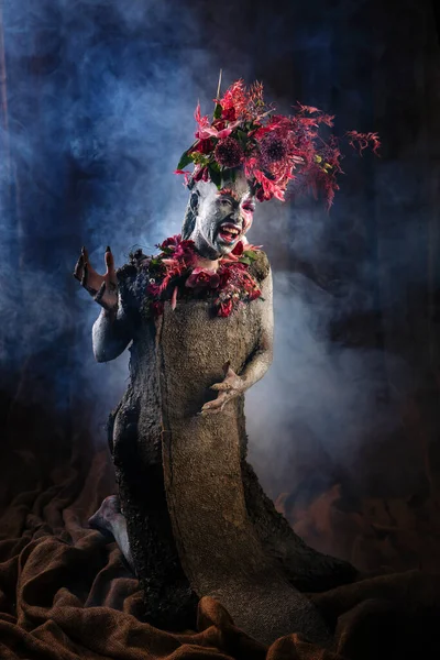 Kil bulaşmış bir kız. Modelde çiçeklerden yapılmış bir başlık var..