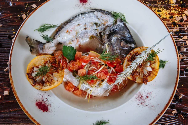 Boiled fish with sauce and fried tomatoes.