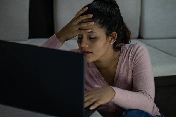 Молодая женщина напряжена телеработой, работающей перед своим ноутбуком