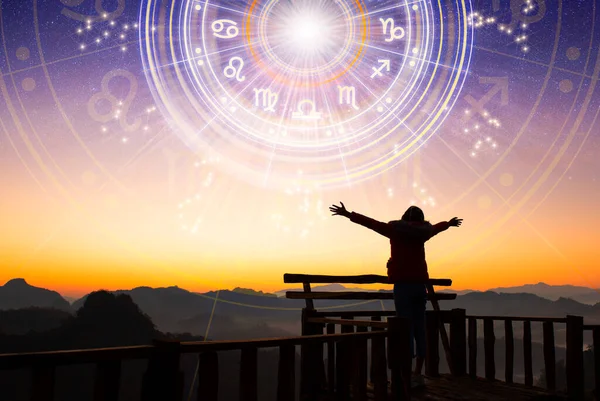 Bir kadın gökyüzüne bakarak el kaldırıyor. Astrolojik tekerlek projeksiyonu, bir burç seçin. Gelecek tahminlere güven, danışmanlık yıldızlarına. Evrenin gücü, astroloji esrarengiz kavram.