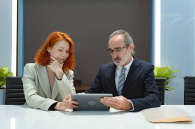 İki mutlu iş adamı yönetici takımı ofiste otururken konuşuyor. Yetişkinler ve kadın ortaklar birlikte çalışıp dijital tablet kullanarak ofiste sohbet ediyorlar..