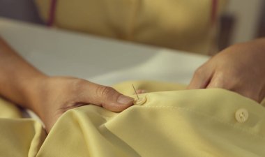 Gömleğinin düğmesine dikiş atan kadın terziyi kapat..