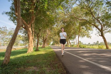 Mutlu genç bir kadın sabahları doğada koşuyor. Sağlıklı ve aktif yaşam tarzı kavramı.