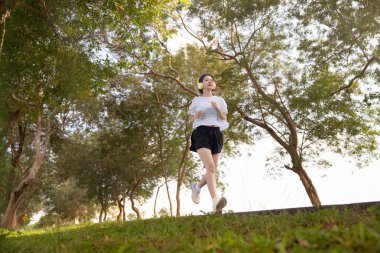 Mutlu genç bir kadın sabahları doğada koşuyor. Sağlıklı ve aktif yaşam tarzı kavramı.