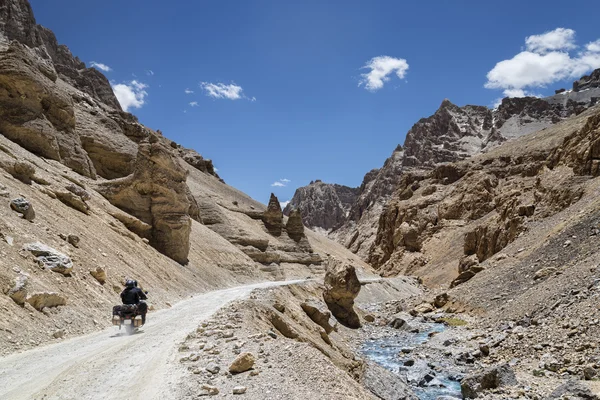 Couple riding on bike among jagged mountains — Stock Photo, Image