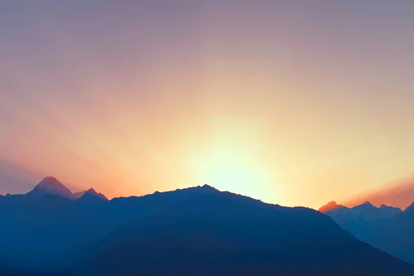 Sun beams above mountain range at dawn — Stock Photo, Image