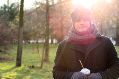 Mutlu genç adam. Gülümsüyor ve kahve fincanı tutuyor..