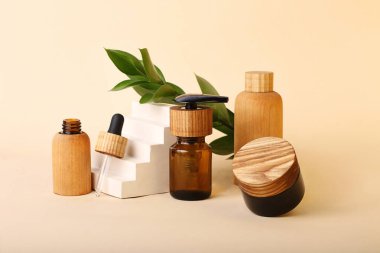 Geometrik kaideye yakın doğal ahşap ve kahverengi camdan çevre dostu borular ve şişeler. Arka planda taze doğal yapraklar. Organik atık kozmetik kavramı sıfır..