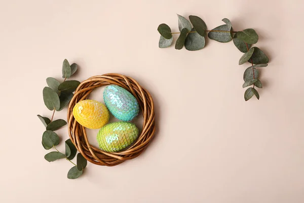Colorful glossy easter eggs in the rattan nest.Natural eucalyptus branch on the back.Happy easter concept. — Stock Photo, Image