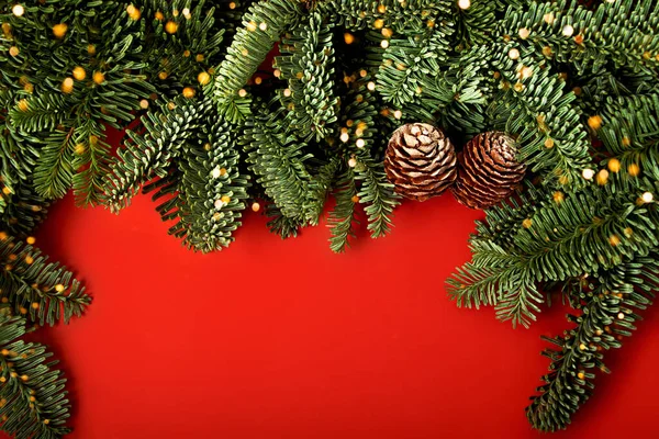 喜庆的红色横向背景 由圣诞树枝条和圆锥做成的边界 上面点着明亮的防波灯 文本复制空间 新年自然布局 — 图库照片