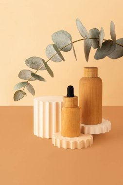 Wooden cosmetics containers on the pastel isometric background.Geometrical podium and fresh eucalyptus branch behind.Earth colors,zero waste containers.Mockup concept. clipart