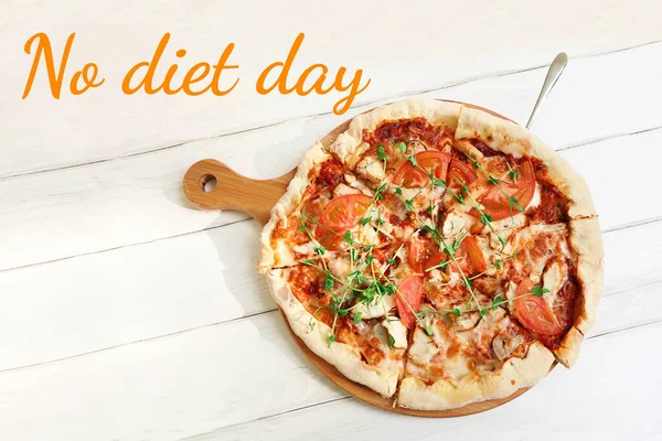 Sliced pizza lies on a wooden cutting board.White table surface under it.Top view photography.Concept of no diet day may sixth.