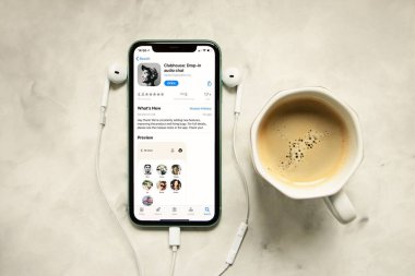 Telefon ekranında kulüp uygulaması olan iPhone, yanında kulaklıklar. Apple.Audio chat 'ten yeni sosyal ağ, sabah rutini kavramı.