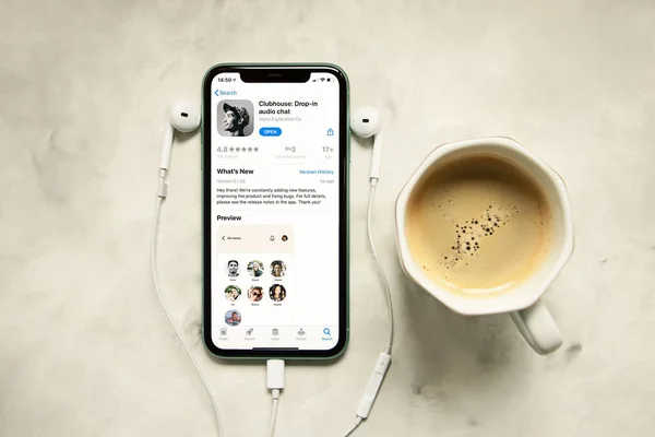 Telefon ekranında kulüp uygulaması olan iPhone, yanında kulaklıklar. Apple.Audio chat 'ten yeni sosyal ağ, sabah rutini kavramı.