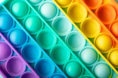 Yeni duyusal oyuncağın üst görünümü - patlat. Gökkuşağı rengi, çukurluk ve dışbükey baloncuklar..